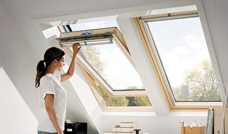 A woman is standing in the sun room with her hands on the window.