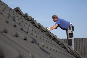 A man is working on the roof of his house.