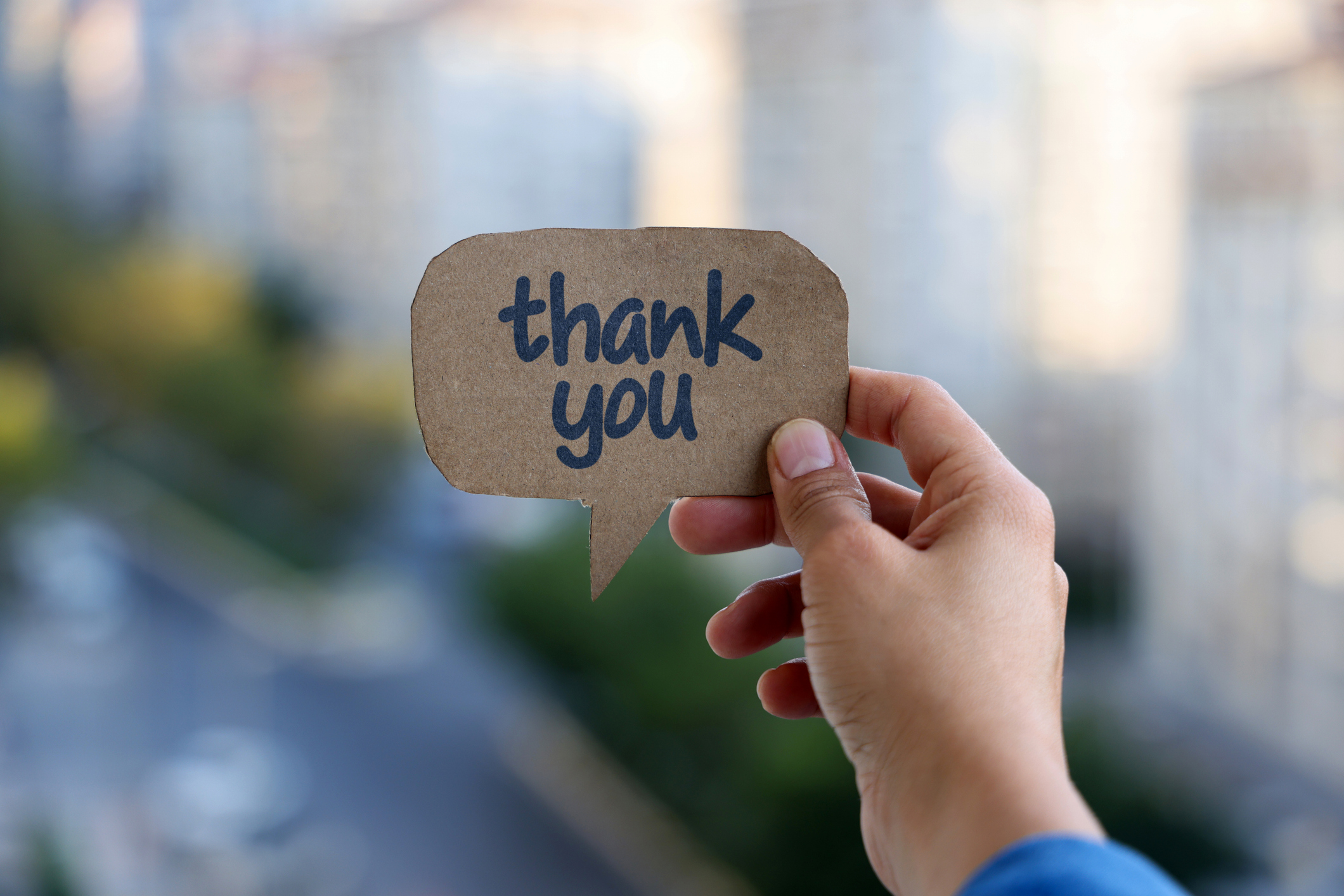 A person holding up a speech bubble with the word " thank you ".